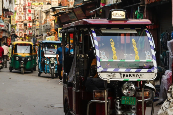 A tuk tuk driving down a busy street